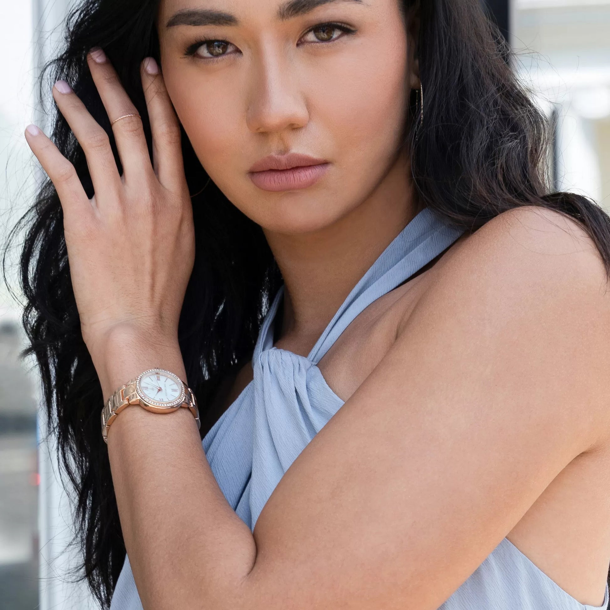 Model wearing Monarchic® Watch - Cosmopolitan - Jackie Edition - Gold link watch with large hoop earrings and soft blue jumpsuit